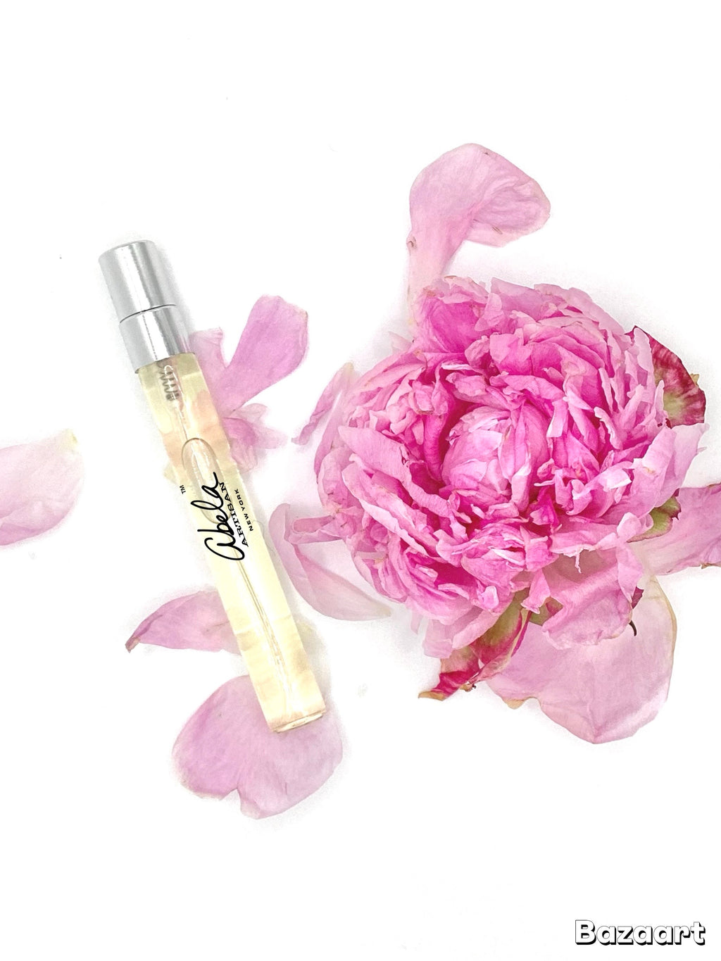 Perfume bottle with a pink Peon flower and petals on a white background