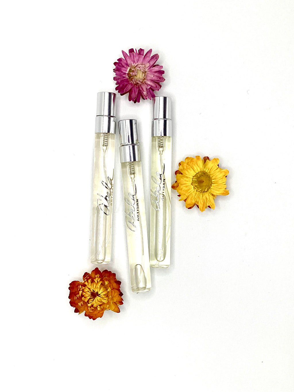 Three small perfume bottles with flowers on a white background